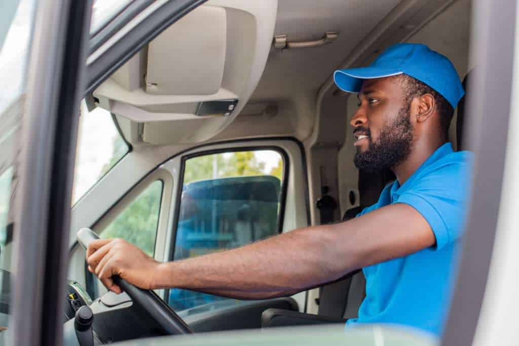 side view of african american delivery man driving van Aria AV Rentals|Event Services